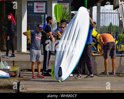 Boat rental crew launch a kayak as holidaymakers don life jackets and choose paddles. Dow's Lake Pavilion, Ottawa, Ontario, Canada. Stock Photo