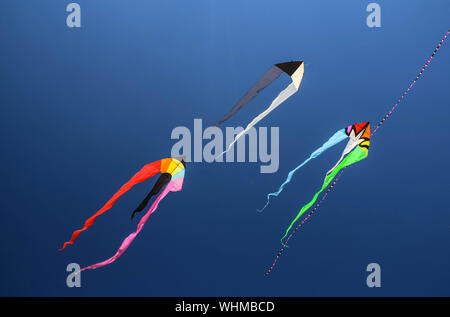 Low Angle View Of Multi Colored Kites Flying Against Clear Blue Sky