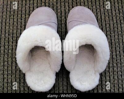 Sheepskin slippers on brown striped carpet Stock Photo