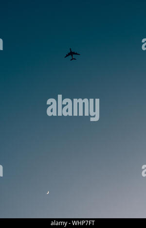 Airplane and crescent moon in the sky Stock Photo