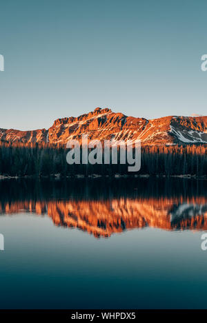 Snowy mountains reflecting in Mirror Lake, in the Uinta Mountains, Utah Stock Photo