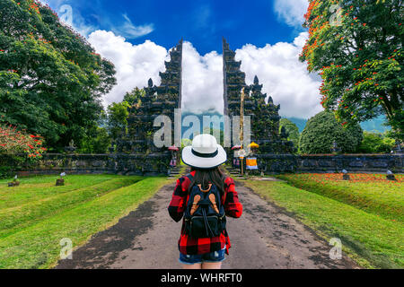 Woman traveler with backpack walking at Big entrance gate in Bali, Indonesia. Stock Photo