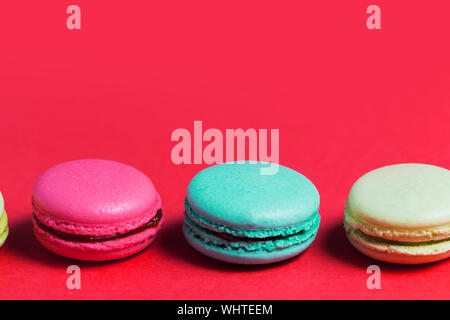 Close up of baked three multicolored macaroons on pink background, copy space. Stock Photo