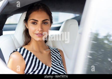 Dark-eyed woman feeling thoughtful while sitting in the car Stock Photo