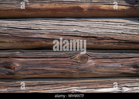 Background texture of old weathered wood cladding on a wall with natural dried planks of cracked and knotty timber in a full frame view Stock Photo