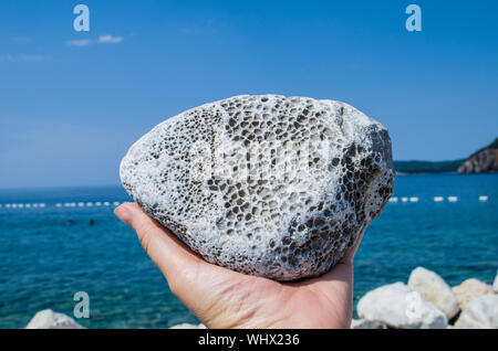 Natural pumice stone in hand on sea background. Natural resources for beauty. Stock Photo