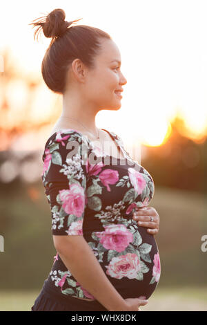 Close up side profile view of pregnant girl holding her pregnant stomach Stock Photo