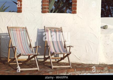 Deck Chairs On Footpath Against Wall
