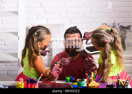 Creativity and imagination. Fathers day and family concept. Girls drawing on man face skin with colorful paints. Body art and painting. Daughters and Stock Photo