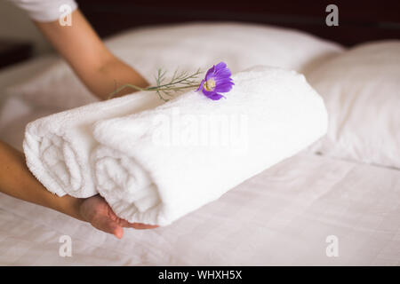 house keeper places towels on a clean white bed for room service. Stock Photo