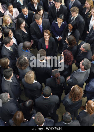 Elevated view of business group looking at female woman standing in middle Stock Photo