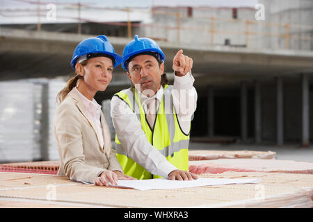 Architect and construction manager discussing plans at site Stock Photo