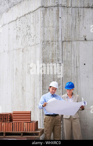 Architect and construction manager reading blueprint at site Stock Photo
