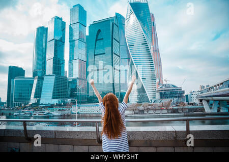 Smiling beautiful woman in a light coat against the backdrop of a skyscrapers business center of a big city. Moscow City Stock Photo