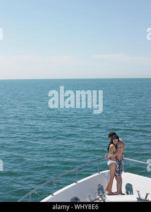Side view of young couple embracing on bow of yacht Stock Photo