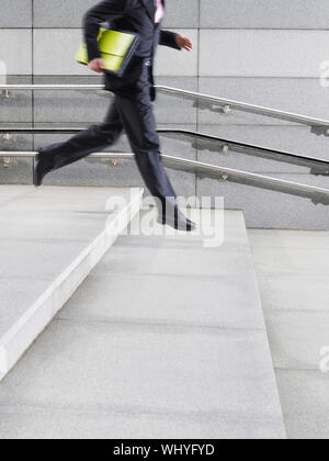 Lowsection side view of a young businessman running down steps outdoors Stock Photo