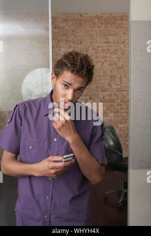 Young African American man holding cellphone in the office Stock Photo