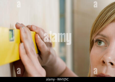 Extreme closeup of a blond young woman using spirit level Stock Photo