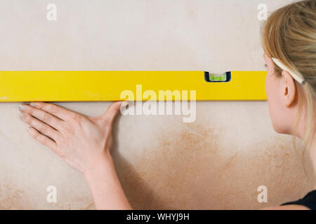 Closeup rear view of a blond young woman using spirit level Stock Photo