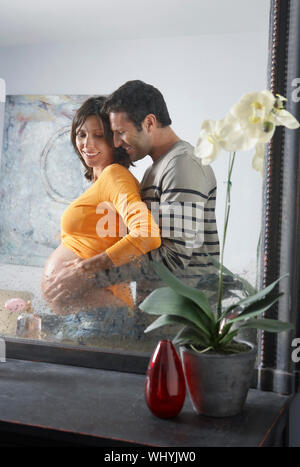 Side view of reflection of a man embracing pregnant woman from behind ...