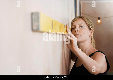 Closeup of a blond young woman using spirit level Stock Photo