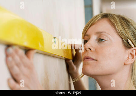 Closeup of a blond young woman using spirit level Stock Photo