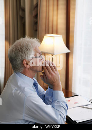 Side view of a middle aged businessman with hands folded sitting at desk Stock Photo