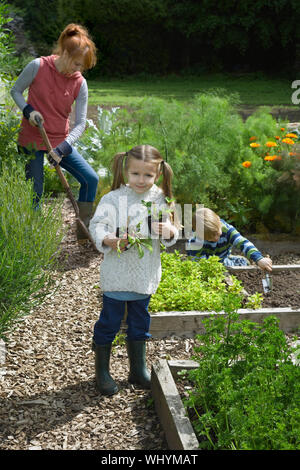 Mother gardening with two children in the field Stock Photo