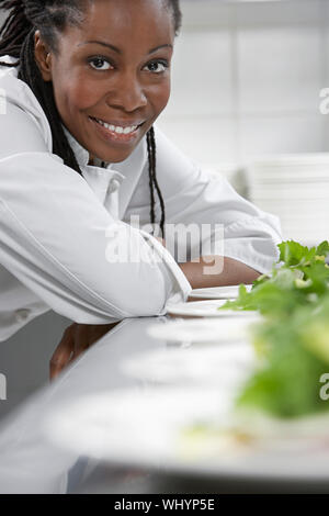 Closeup portrait of a smiling female chef preparing salad in kitchen Stock Photo