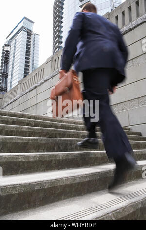 Full length rear view of a businessman with briefcase ascending steps Stock Photo