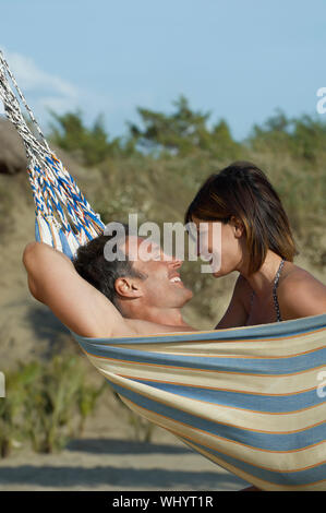 Side view of a young couple in hammock smiling Stock Photo