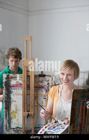 Young male and female students painting at easels in art class Stock Photo
