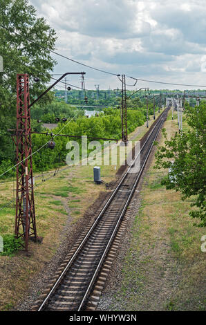 Top view of the electrified railway line that goes to bridge over the river Stock Photo