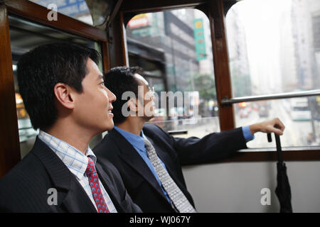 Side view of two businessmen sitting in double decker tram Stock Photo