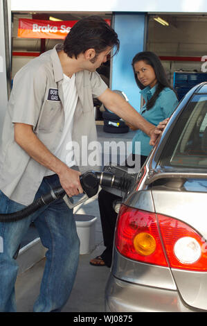 Woman watching gas station attendant pumping gas Stock Photo