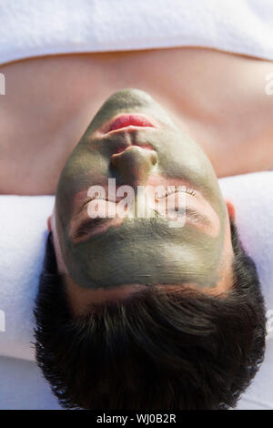 Young woman wearing mud facial mask at health spa, close-up Stock Photo