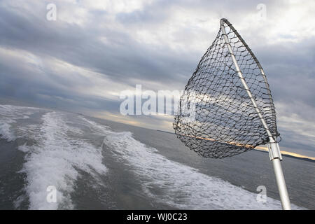 Fishing net sticking on back of speeding fishing boat Stock Photo