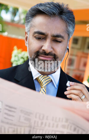 Mature Indian businessman reading newspaper Stock Photo