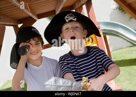 A preadolescent boy wearing pirate hat with his friend looking through telescope Stock Photo