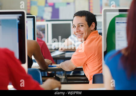 Portrait of a happy male student with classmates in computer laboratory Stock Photo