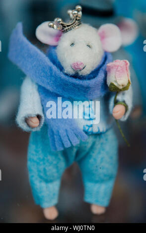toy mouse in clothes handmade wool in the hands of a rose, a crown on his head, selective focus. Stock Photo
