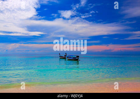 Sun setting over boats in the water on Koh Lipe Stock Photo