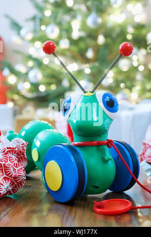 Closeup of caterpillar toy in front of Christmas tree Stock Photo