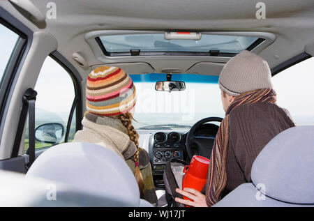 Rear view of young couple wearing warm clothing in car during road trip Stock Photo
