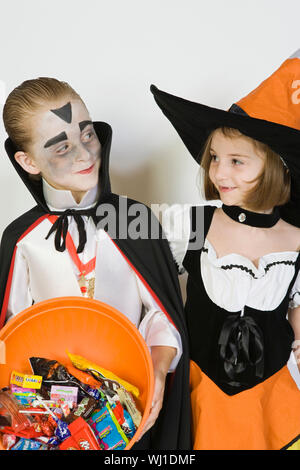 Happy preadolescent friends in Halloween outfit looking at each other isolated over white background Stock Photo