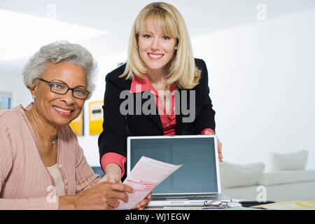Portrait of senior African American woman being assisted by financial advisor for paperwork Stock Photo