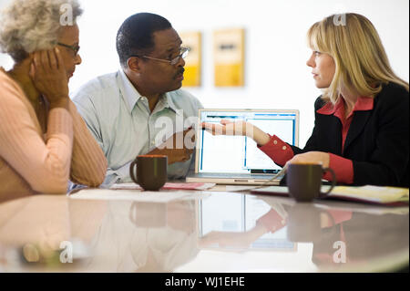 Middle aged female financial advisor explaining investment plans to a senior couple at home Stock Photo
