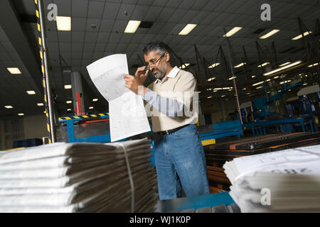 Middle aged man reading newspaper in the factory Stock Photo
