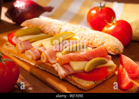 ciabatta sandwich with ham, cheese, tomato on wooden board Stock Photo