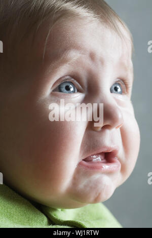 Closeup of a baby girl crying against gray background Stock Photo